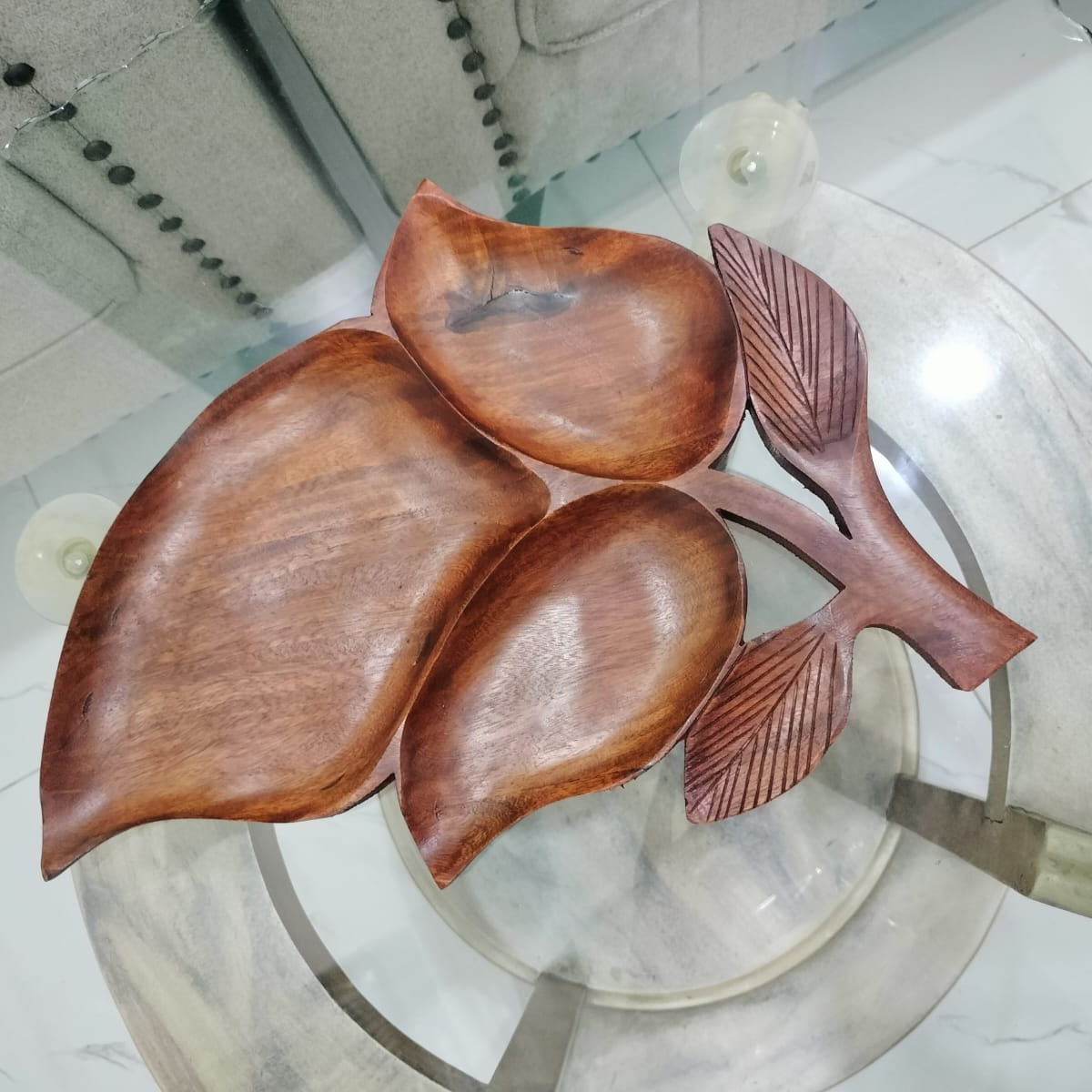 Wooden leaf-shaped items on a glass surface with a tiled floor background