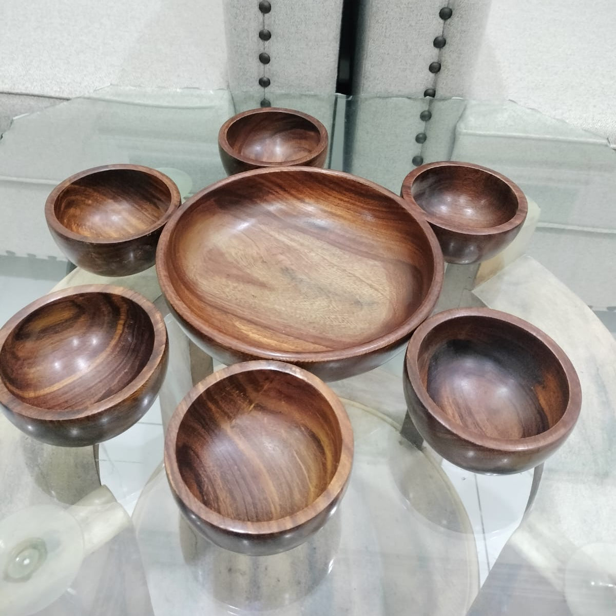 Set of wooden bowls on a glass table with a neutral background