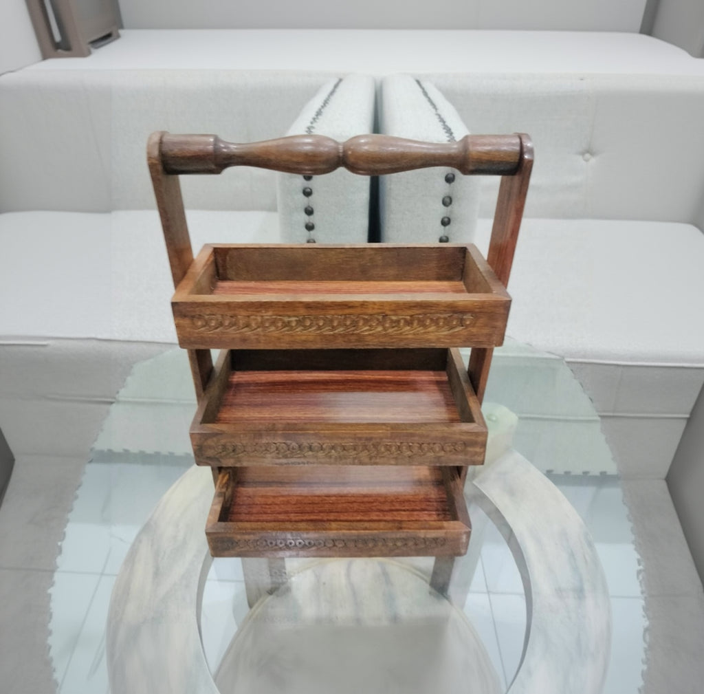 Wooden three-tiered tray on a glass surface with a white background